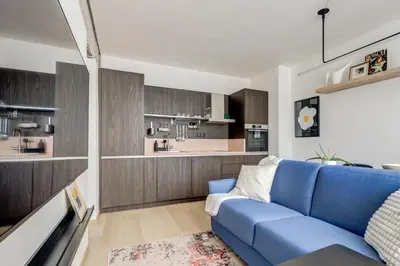 a living room with a blue couch and a kitchen at Splendid 1BDMApartment Near Shopping Mall & Metro in Sofia
