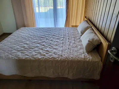 a bed with white sheets and pillows next to a window at Pirin Golf Villa Sokol in Bansko