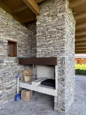 a stone wall with a fireplace in a patio at Pirin Golf Villa Sokol in Bansko
