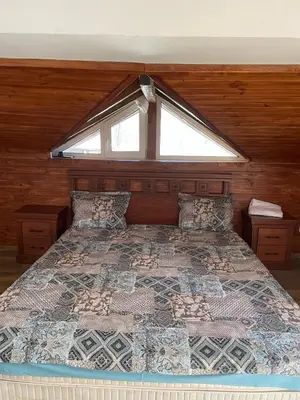 a bedroom with a large bed with a window at Guest House Robin Hud in Cherni Osŭm
