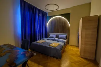 a bedroom with a bed and a table and blue drapes at 1 Minute Walk to Main Street Vitoshka, NDK, Free Parking, 2 BDR in Sofia