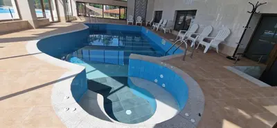 a swimming pool in a building with chairs around it at Nara in Pchelin