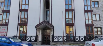 a white building with a door and cars parked in front at Comfy Studio in Bansko