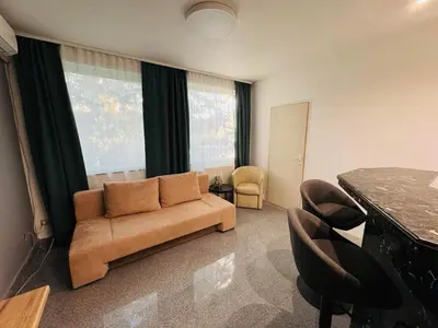 a living room with a couch and a large window at Green Accent Apartment in Sofia