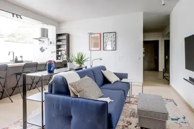a living room with a blue couch and a kitchen at Modern 1BDMApartment Near Shopping Mall & Metro in Sofia