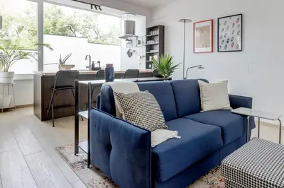 a living room with a blue couch and a kitchen at Modern 1BDMApartment Near Shopping Mall & Metro in Sofia