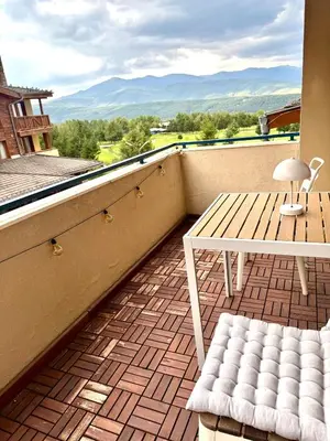 a balcony with a table and a bench and a view at Pirin Golf Cozy Mountain Apartment with Views of Pirin & Rila in Bansko