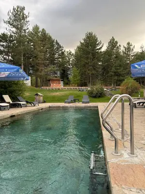 a swimming pool with chairs and aicket at Pirin Golf Cozy Mountain Apartment with Views of Pirin & Rila in Bansko