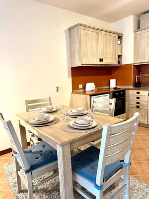 a dining room table with chairs and a kitchen at Pirin Golf Cozy Mountain Apartment with Views of Pirin & Rila in Bansko