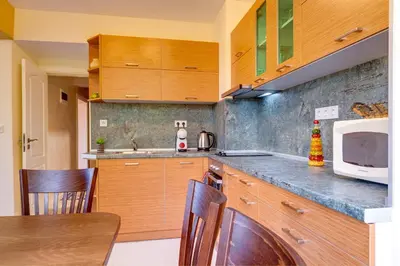 a kitchen with wooden cabinets and a table and a microwave at Bright retreat with Balcony & Mountain Views by Flat Manаger in Smolyan