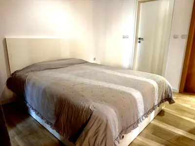 a bed in a white room with a wooden floor at Studio Sredec 77 in Plovdiv