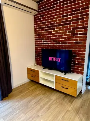 a flat screen tv sitting on a stand next to a brick wall at Studio Sredec 77 in Plovdiv
