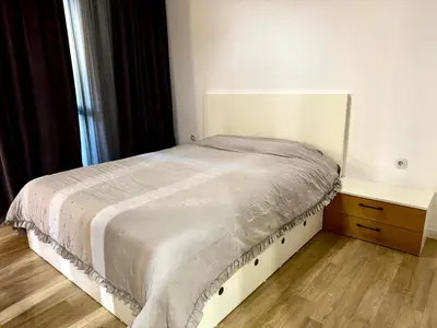a bedroom with a white bed and a wooden floor at Studio Sredec 77 in Plovdiv