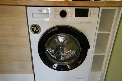a white washing machine sitting under a counter at Apartment near a Metro Station in Sofia