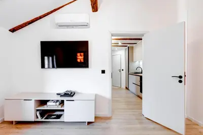 a white kitchen with a desk and a tv on the wall at City Gem 1BDRM 200m Sofia Statue in Sofia