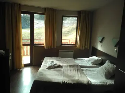 a bedroom with two beds and a large window at Apart Hotel Forest Nook 3 Pamporovo in Pamporovo