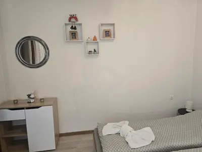a bedroom with a bed and a mirror and a table at Peshtera Cozy Apartment in Peshtera