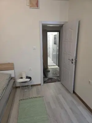 a room with a bed and a door and a hallway at Peshtera Cozy Apartment in Peshtera