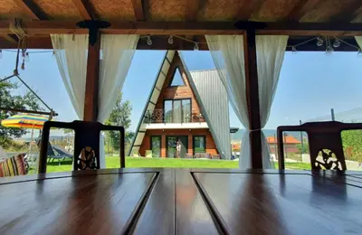 a wooden table with curtains in front of a house at Magnika in Sapareva Banya