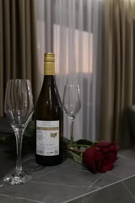 a bottle of wine and two wine glasses on a table at Ивелия Хотел и Спа - Ivelia Hotel & SPA in Dŭbnitsa