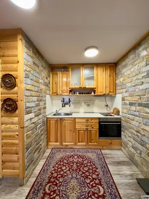 a kitchen with wooden cabinets and a brick wall at Villa Margarita 1 in Semkovo