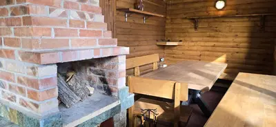 a room with a brick fireplace and a table and benches at Villa Margarita 1 in Semkovo