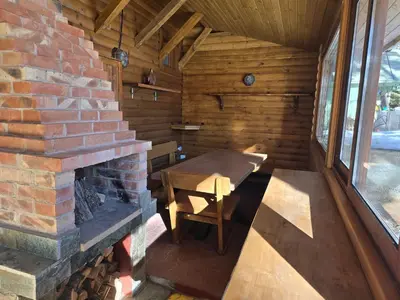 a wooden cabin with a fireplace and a wooden table at Villa Margarita 1 in Semkovo