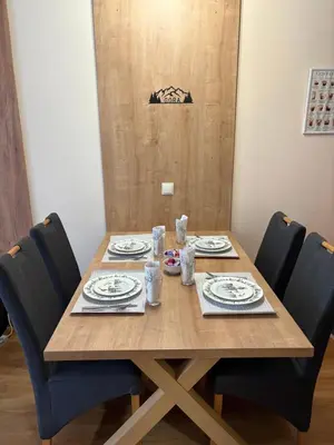 a wooden table with chairs around it with plates and dishes at Apartment GORA in Borovets