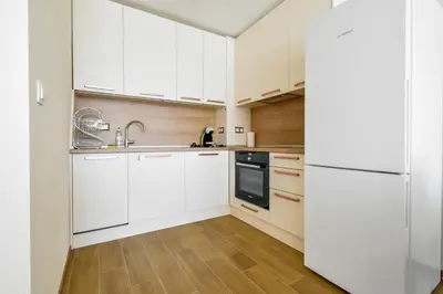 a kitchen with white cabinets and a refrigerator at Contemporary City Stay by Flat Mаnager in Sofia