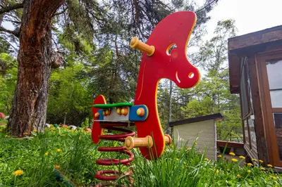 a red toy horse statue in a garden at Комплекс Родопска среща - Къщи и Апартаменти in Batak