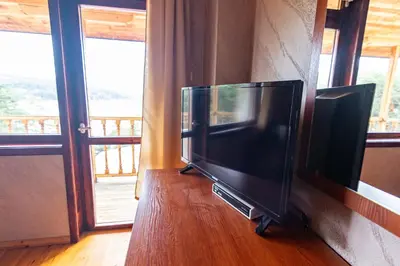 a flat screen tv sitting on a wall next to a window at Комплекс Родопска среща - Къщи и Апартаменти in Batak