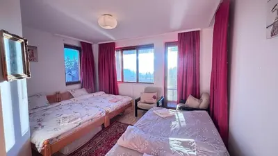 a bedroom with two beds and a chair and windows at Maisonette on the slope in Manastir 3 in Pamporovo