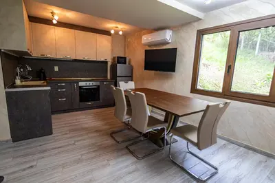 a kitchen with a dining room table and chairs at Комплекс Родопска среща - Къщи и Апартаменти in Batak