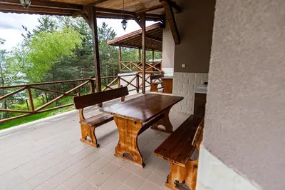 a wooden table and a bench on a porch at Комплекс Родопска среща - Къщи и Апартаменти in Batak