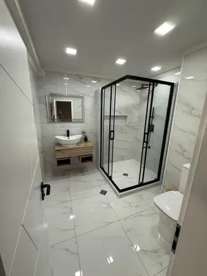 a white bathroom with a shower and a sink at Grand Trio Apartment in Plovdiv