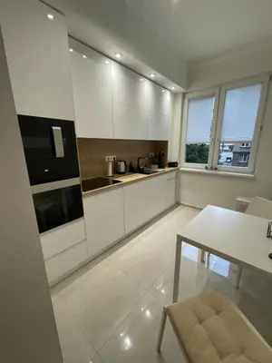 a kitchen with white cabinets and a table and window at Emlex Stylish Apartment in the Heart of Sofia in Sofia