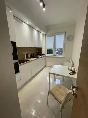 a kitchen with white cabinets and a table and chairs at Emlex Stylish Apartment in the Heart of Sofia in Sofia