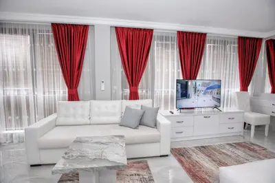 a living room with a white couch and red curtains at Парк Апарт-Хотел Виктория 1 in Sandanski