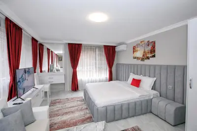 a bedroom with a bed and a tv and red curtains at Парк Апарт-Хотел Виктория 1 in Sandanski