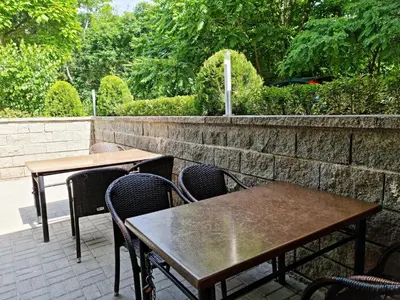 two tables and chairs on a patio with a stone wall at Парк Апарт-Хотел Виктория 1 in Sandanski