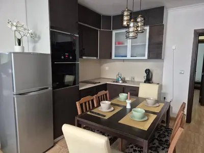 a kitchen with a table with chairs and a refrigerator at 1А1 Apartament in Pamporovo