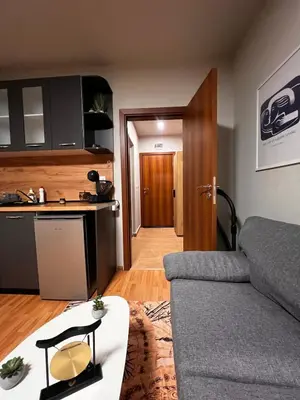 a living room with a couch and a kitchen at Apartment near the ski lift with a private parking in Bansko