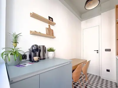 a kitchen with white cabinets and a table with plants at Lift - Duplex - King Beds - 5min to Vitosha in Sofia