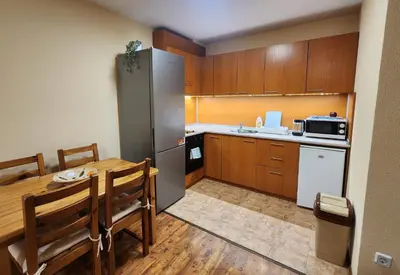 a kitchen with a table and a stainless steel refrigerator at Mountain Dream apartment near ski road in Bansko