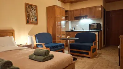 a bedroom with a bed and two chairs and a kitchen at Margarita Mountain Apartments in Tsigov Chark