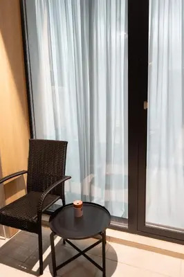 a chair and a table in a room with a window at All Seasons Plovdiv - Fast Wi-Fi, AC, Balconies in Plovdiv