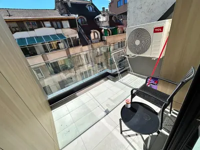 a balcony with a table and a chair on a building at All Seasons Plovdiv - Fast Wi-Fi, AC, Balconies in Plovdiv