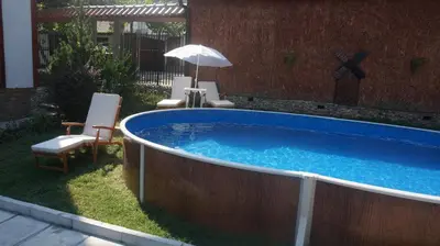 a large swimming pool with chairs and an umbrella at Guest House Simona in Sapareva Banya