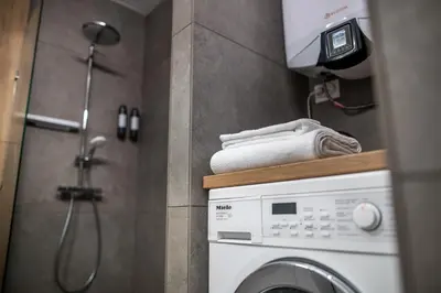 a bathroom with a washing machine and a shower at ARHEYA 2 apart АРХЕЯ 2 апартамент за гости in Karlovo