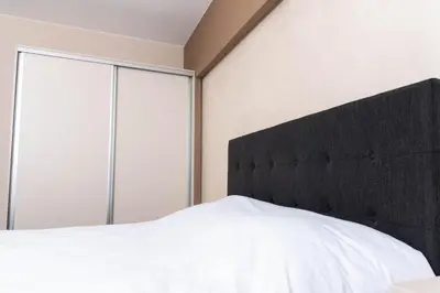 a bedroom with a white bed with a black headboard at Apartment Maritsa View 2 in Plovdiv
